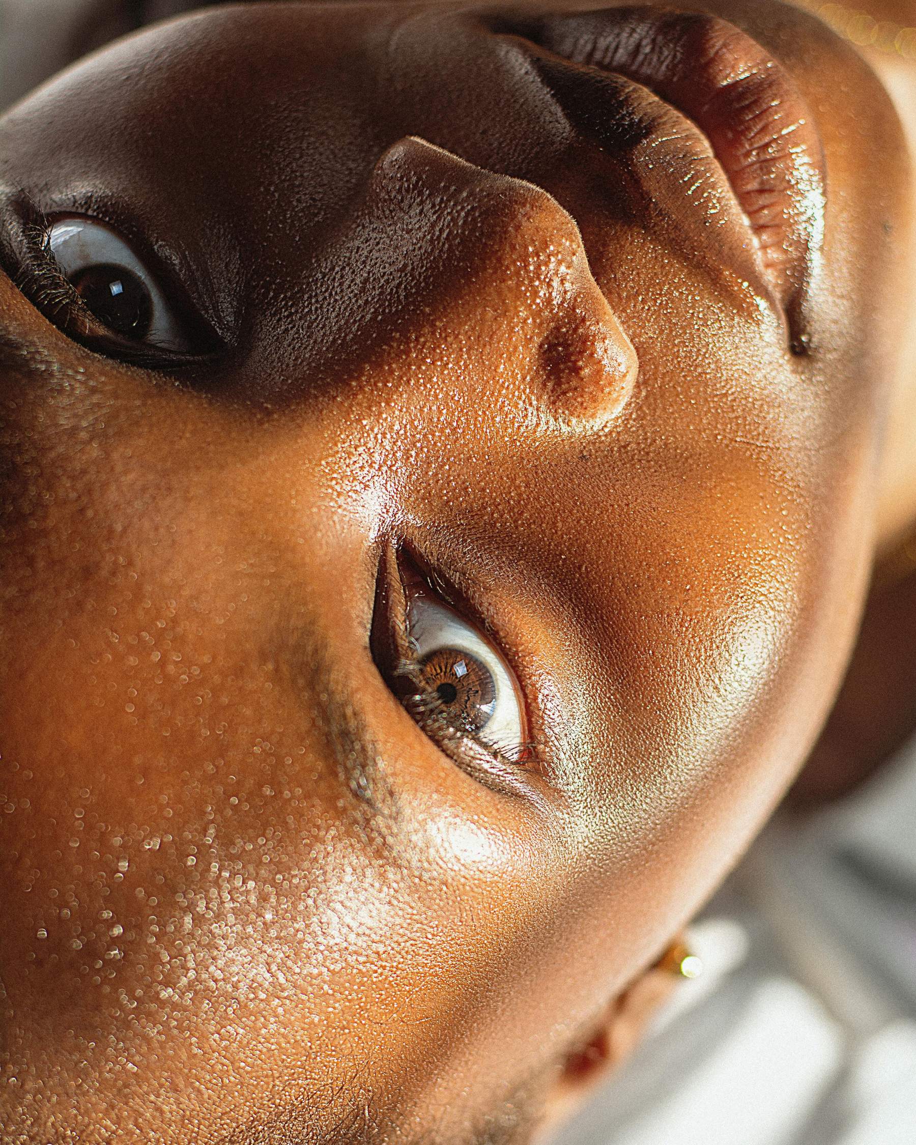 Portrait en gros plan d’une femme aux tons de peau chauds, montrant une texture de peau naturelle sous une lumière douce.