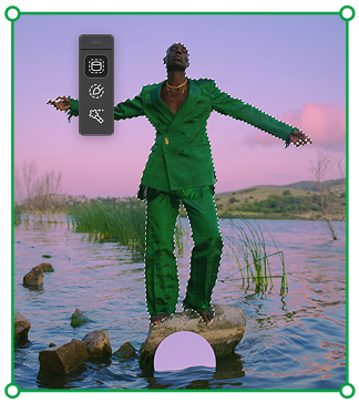 Person in a green suit standing on a rock in a calm lake at sunset with arms outstretched